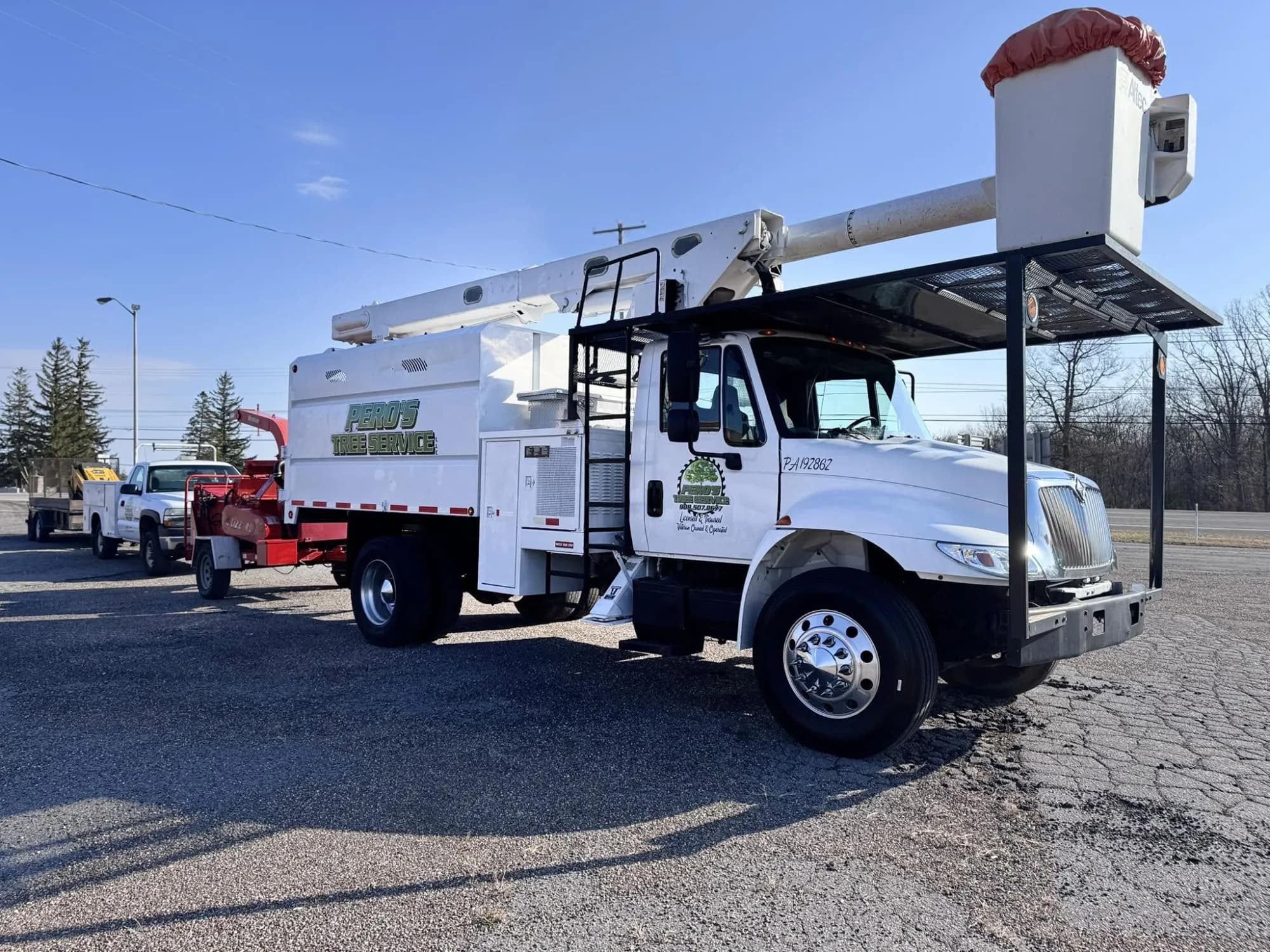 Peros Tree Service bucket truck with Altec aerial lift, wood chipper and crew pickup